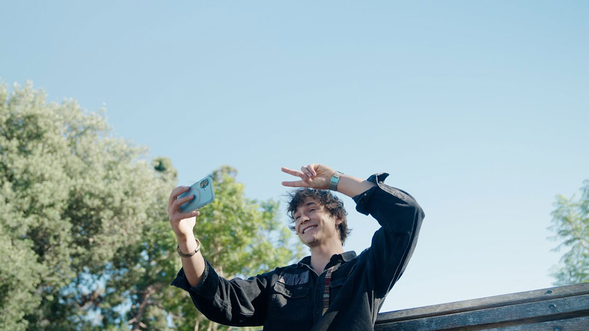 A student filming themselves with their smartphone and holding up the peace sign