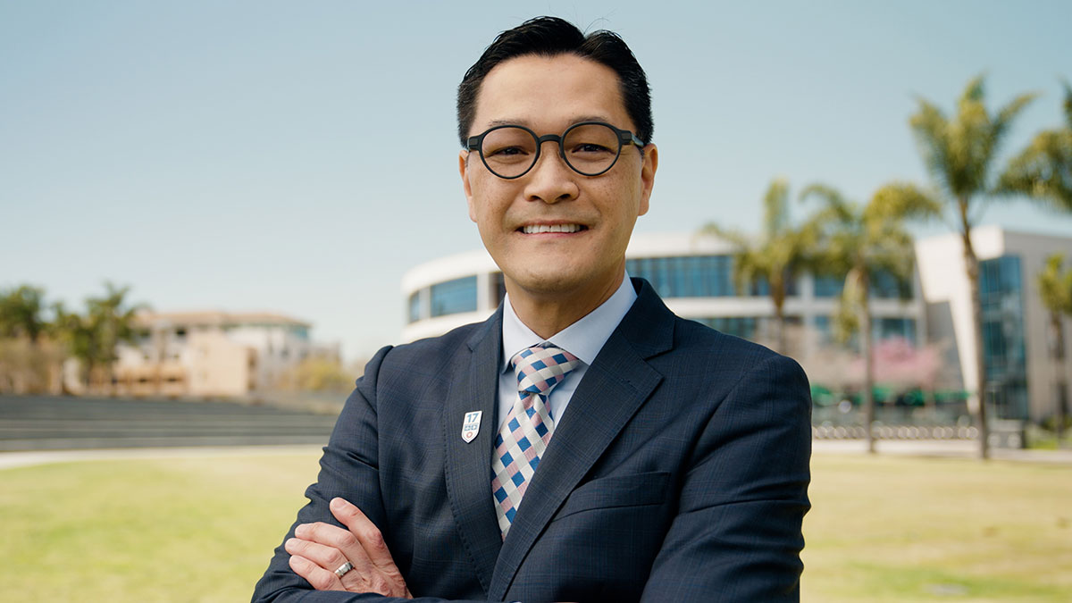 Tom Poon standing in Lawton Plaza with the William H Hannon Library in the distance